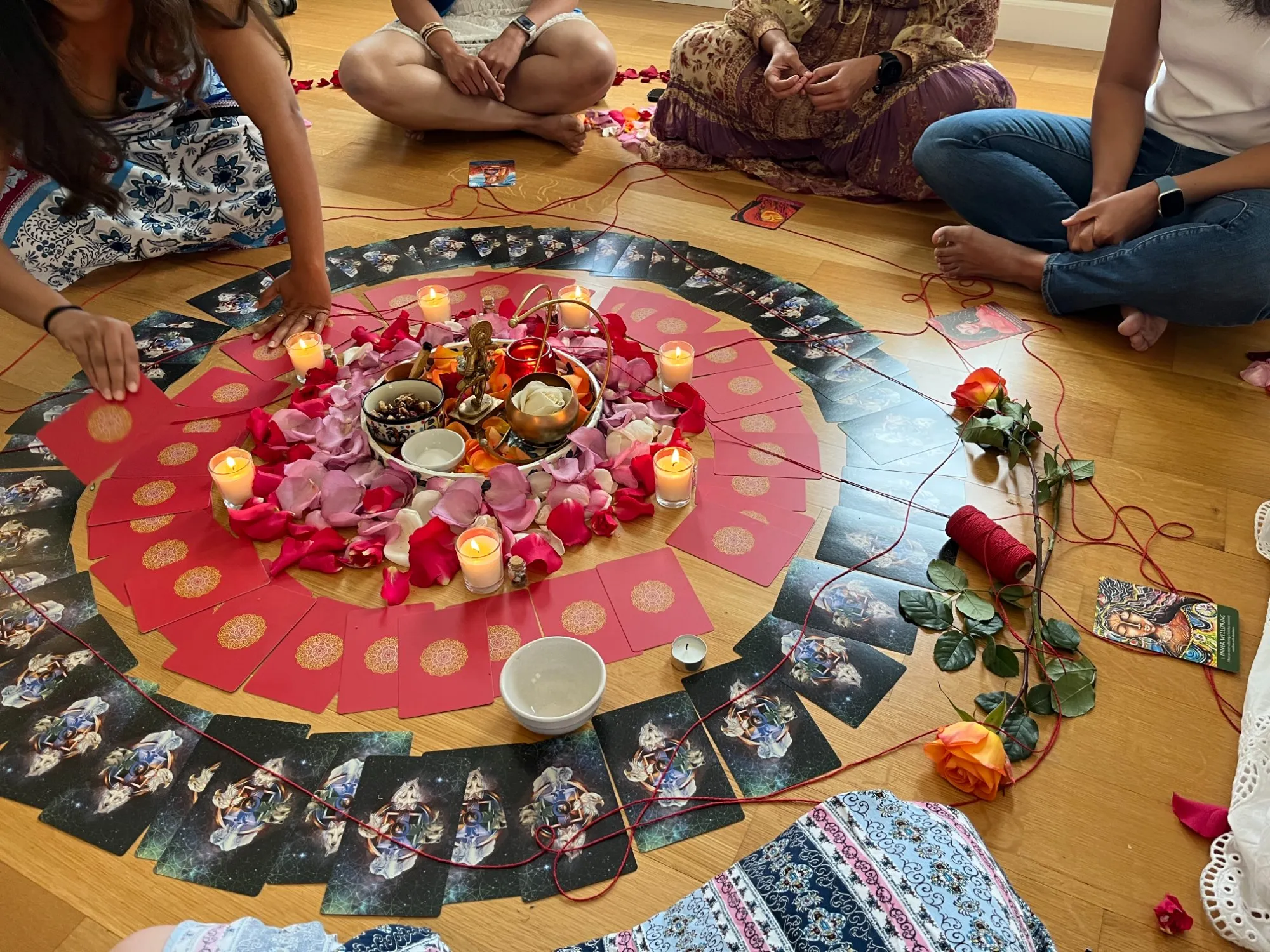 Sacred ritual ceremony with rose petals, candles, and oracle cards arranged in a mandala